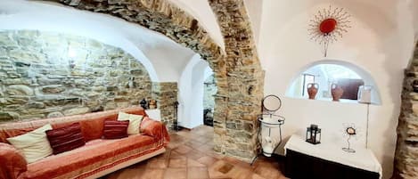 A cozy room with a stone wall, a red sofa, and a white table with decorative items.