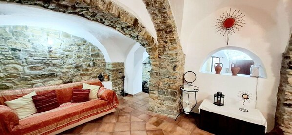 A cozy room with a stone wall, a red sofa, and a white table with decorative items.