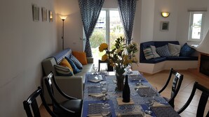 Un coin repas avec une table dressée pour quatre personnes, un canapé et un téléviseur en arrière-plan.