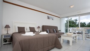 Una habitación de hotel con dos camas, un balcón y zona de comedor.