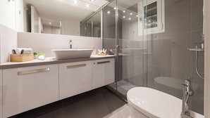 Une salle de bain moderne avec une douche à parois de verre, un lavabo blanc et des toilettes.