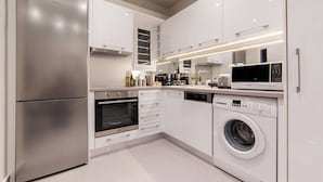 Une cuisine moderne dotée d’appareils électroménagers en acier inoxydable, de meubles blancs et d’un éclairage intégré.