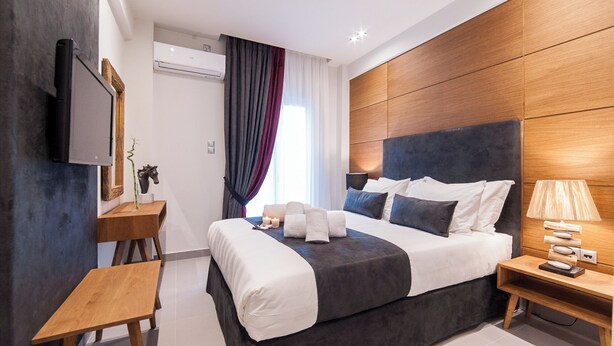 Une chambre d’hôtel moderne équipée d’un lit, d’une table de chevet, d’une lampe et d’un téléviseur fixé au mur.