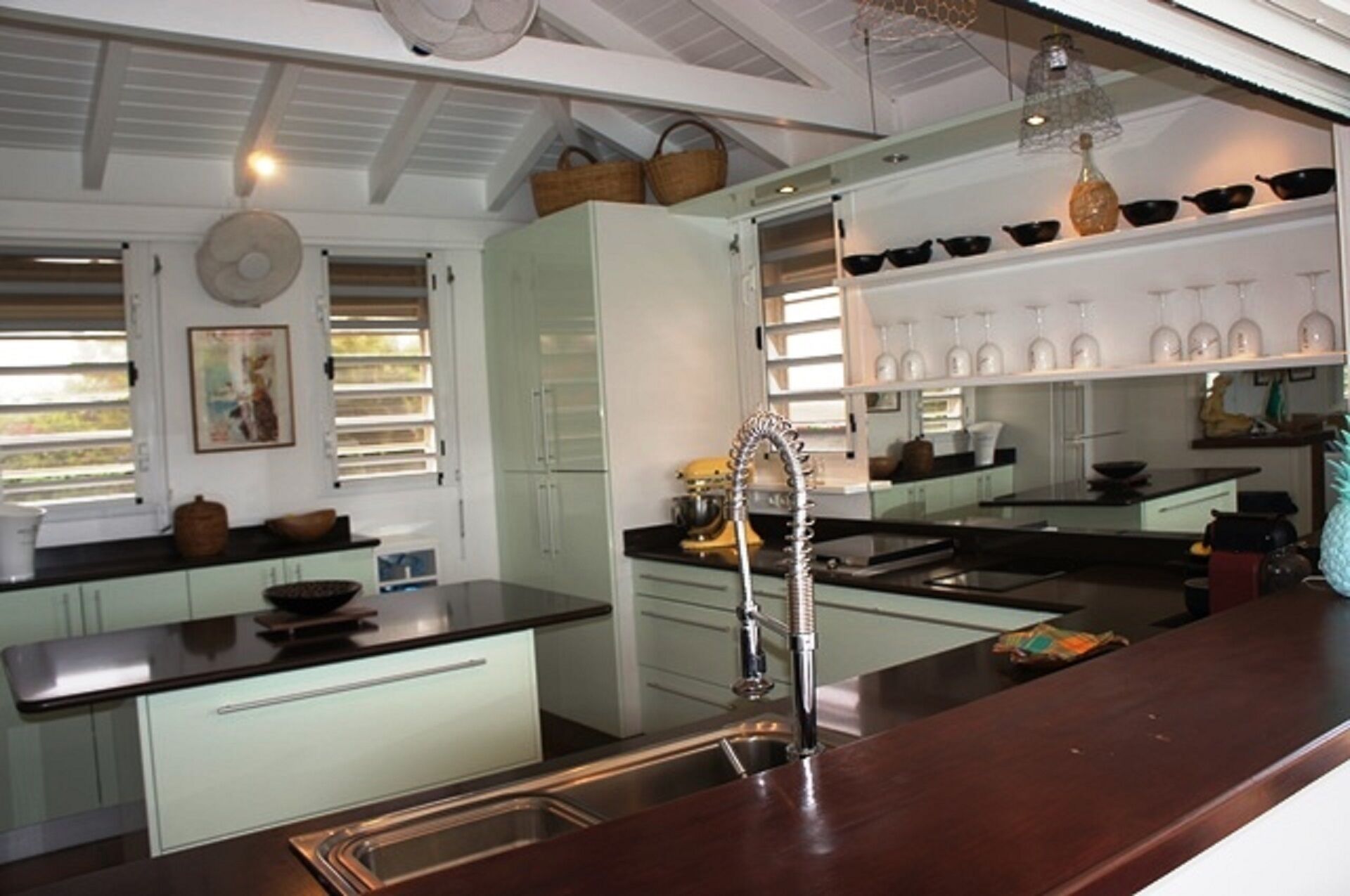 A modern kitchen with white cabinets, a stainless steel sink, and a variety of kitchen utensils on the counter.