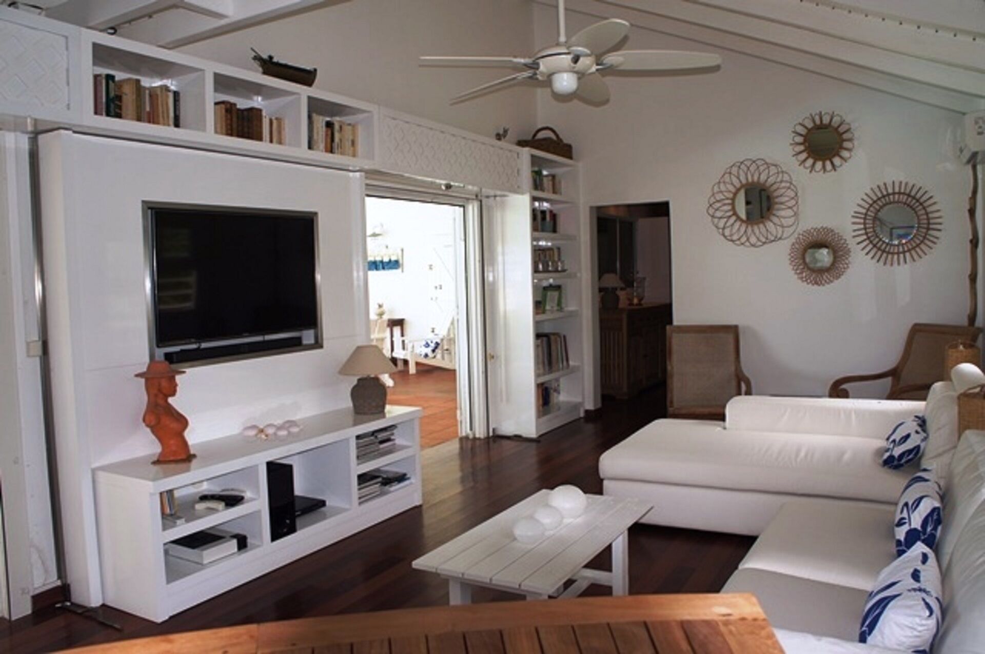 A living room with a flat-screen TV, white sofas, a coffee table, and a bookshelf.