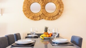 A dining table with two plates, a bowl of fruit, and two wine glasses. - 3 bedroom villa in quiet complex with swimming pools / private wifi / UKTV (Corralejo)