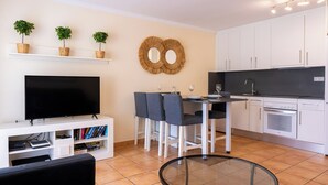 A modern living room with a flat-screen TV, a glass coffee table, and a seating area with a sofa and chairs. - 3 bedroom villa in quiet complex with swimming pools / private wifi / UKTV (Corralejo)