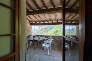 A covered outdoor seating area with stone walls and a view of green hills. - Beautiful Tuscan farmhouse in the countryside with swimming pool (Mercatale)