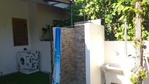 A small outdoor bathroom with a shower, a toilet, and a washing machine. - San Teodoro: 600 m. from the beach and the center, air conditioning, Wi-Fi  (San Teodoro)