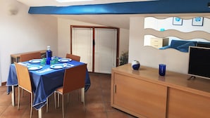 Ein Essbereich mit einem Tisch für zwei Personen, einem Schrank mit Fernseher und einem Dachfenster.