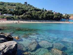 Una zona costera con aguas cristalinas, formaciones rocosas y una playa de arena.
