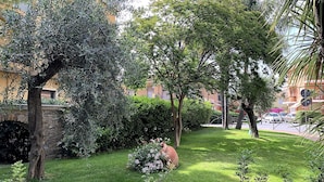 Ein gepflegter Garten mit einer Steinbrücke, üppigem Grün und verschiedenen Bäumen.