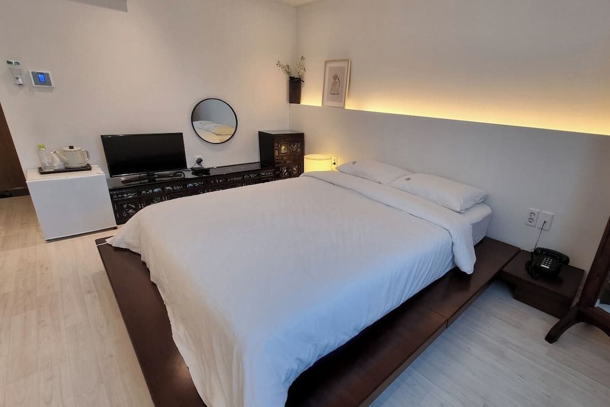 A modern bedroom with a large bed, bedside tables, a TV, and a bedside lamp.