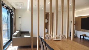 Un salon moderne avec un canapé, une table à manger agrémentée de verres, et un téléviseur fixé au mur.