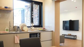 Une cuisine moderne avec une fenêtre, un coin repas comprenant une table et des chaises, et un téléviseur à écran plat fixé au mur.