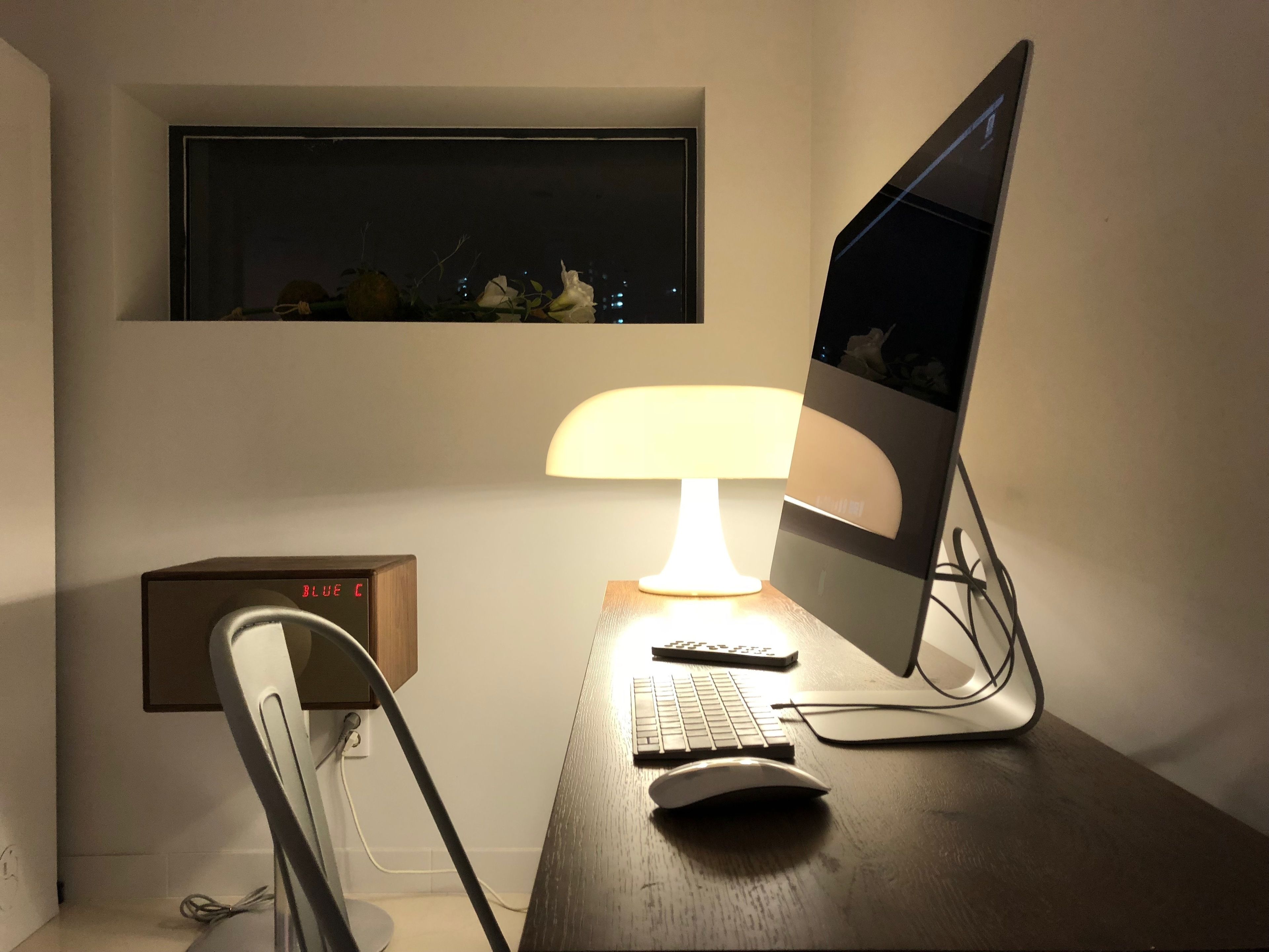 A desk with a computer, keyboard, and mouse, a lamp, and a clock.