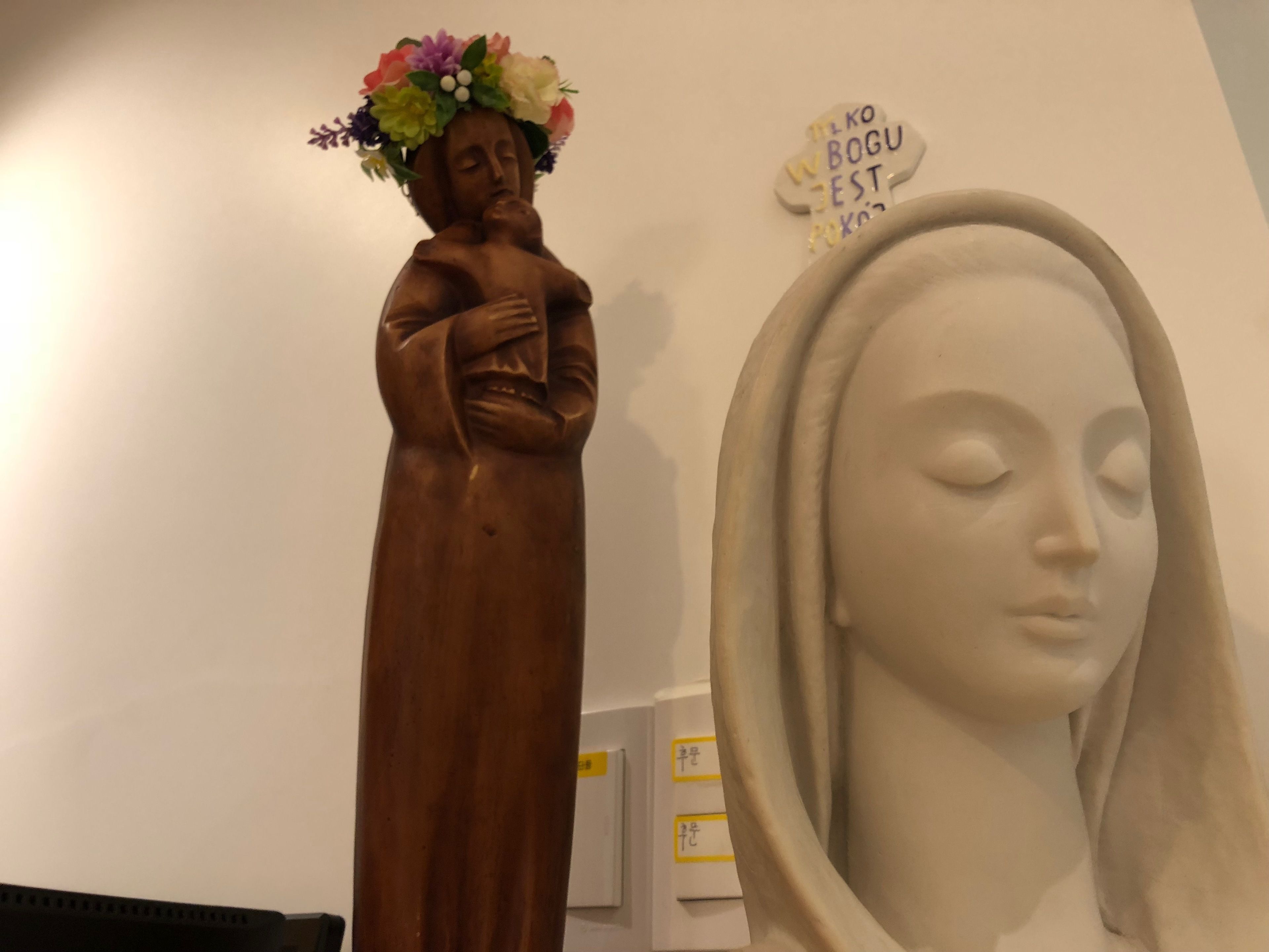 Une statue en bois, ornée d’une coiffe florale et d’un buste blanc recouvert d’un voile.