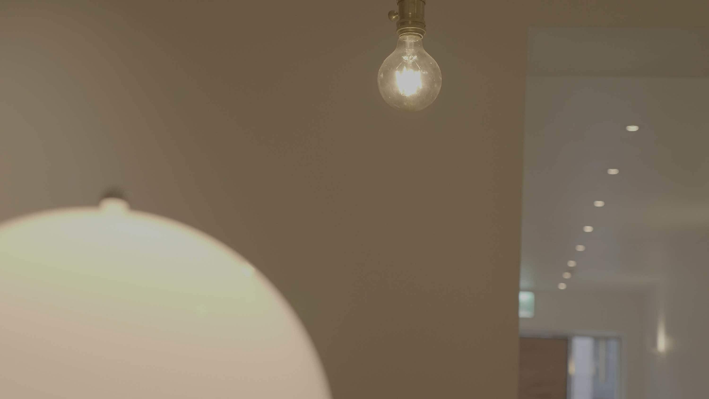 A room with a hanging light bulb and a large, soft-glow lamp.