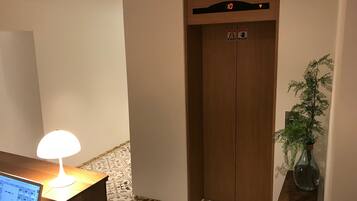 Un ascensor con una pantalla digital que muestra el número 10, un símbolo de mano y un símbolo de silla de ruedas.