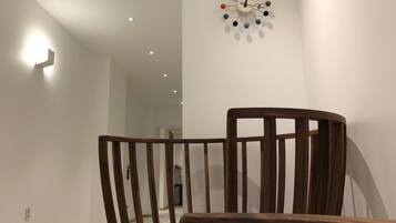 A wooden chair in a room with a modern clock on the wall.