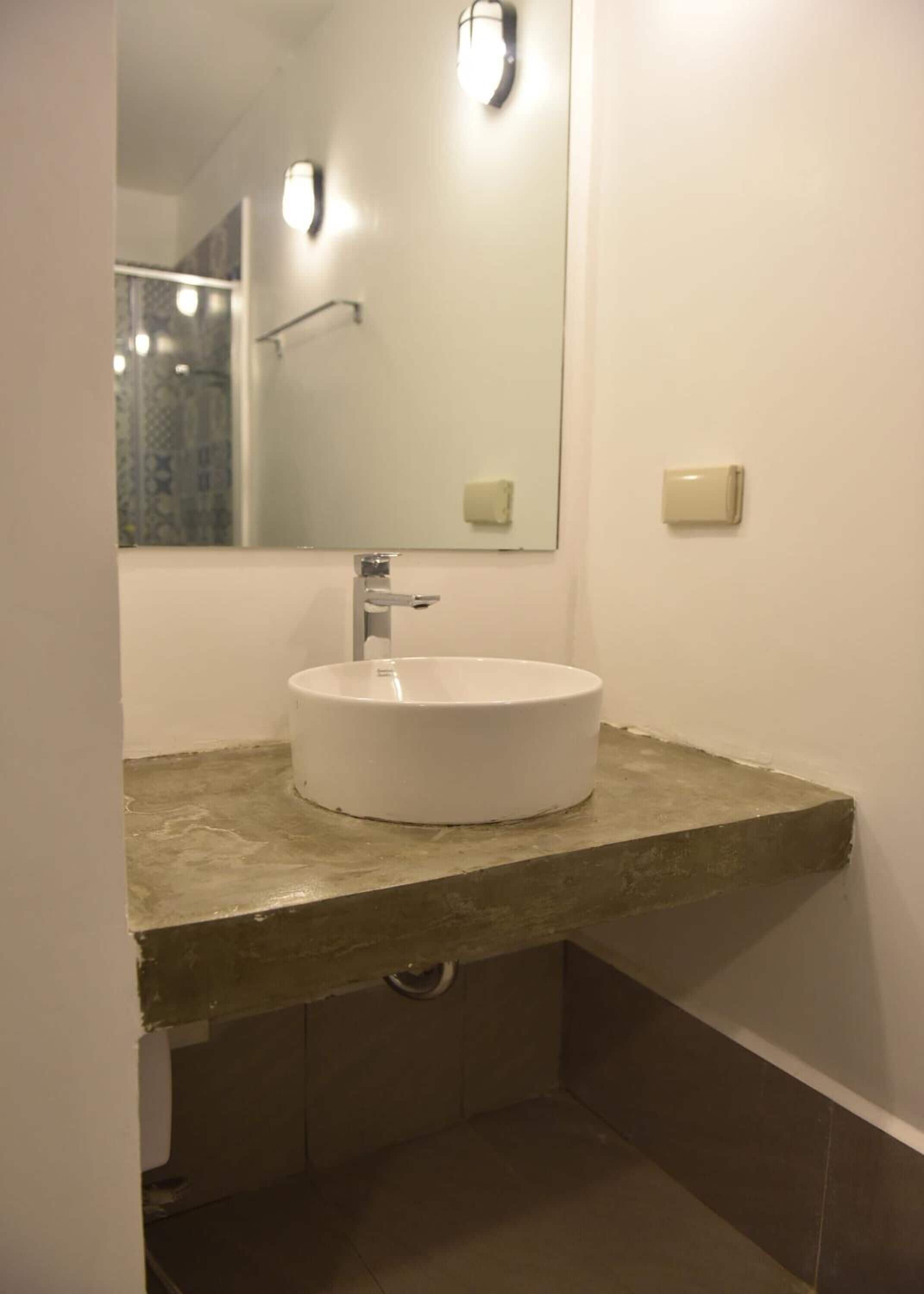 Un baño con lavamanos blanco, un espejo y una lámpara.