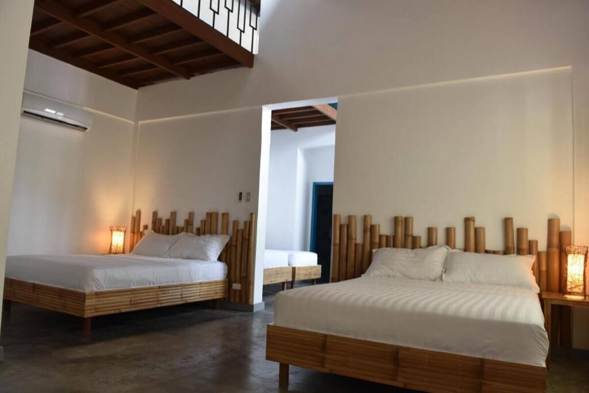 A bedroom with two beds, wooden headboards, and bedside lamps.