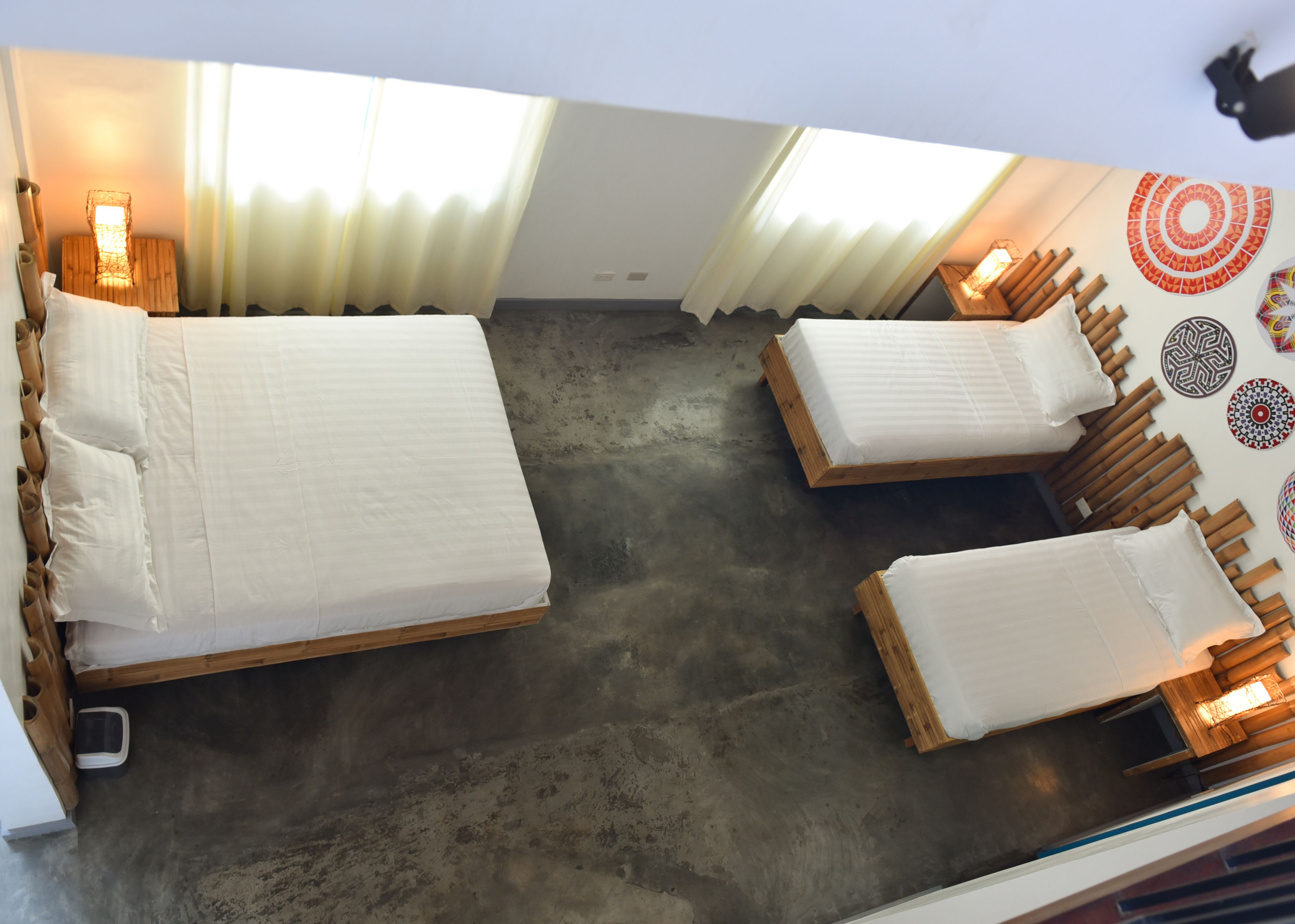 A room with two wooden beds, a concrete floor, and a wall with decorative plates.