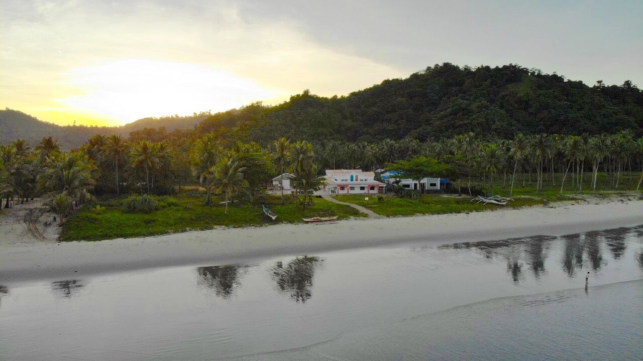 Une propriété située sur la côte, avec une plage, une maison et un bateau.