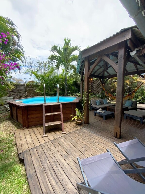 Una terraza de madera con un jacuzzi, sillones de descanso y una zona de estar cubierta.