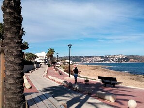 A coastal promenade with a paved walkway, benches, and a person walking a dog. - 0210 Villa Toscamar with private pool (Javea / Xàbia)
