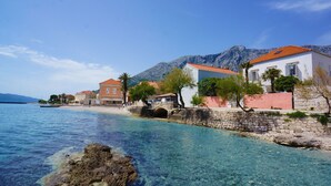 Eine Küstenstadt mit klarem Wasser, Steingebäuden und einer Bergkulisse.