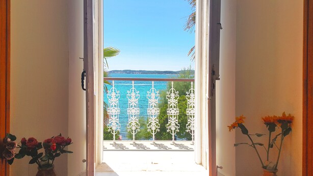 Ein Durchgang zu einem Balkon mit Blick auf das Meer und einem dekorativen Metallgeländer.