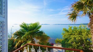Ein Balkon mit Blick auf das Meer, Palmen und vorgelagerte Inseln.