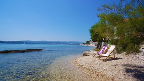 Ein Strand mit klarem Wasser, felsigem Ufer und einem Liegestuhl mit einem violetten Handtuch.