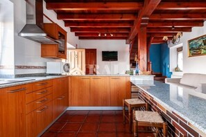 A kitchen with wooden cabinets, a central island, and a tiled floor. - Apto Tapia 2 - rural apartment in Luces (Colunga), Northern Spain | 6 guests (San Telmo)