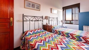 A bedroom with two beds, a wooden door, and a window. - Apto Tapia 2 - rural apartment in Luces (Colunga), Northern Spain | 6 guests (San Telmo)