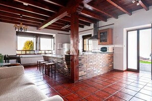 A kitchen with a brick backsplash, wooden beams, and a view through the window. - Apto Tapia 2 - rural apartment in Luces (Colunga), Northern Spain | 6 guests (San Telmo)