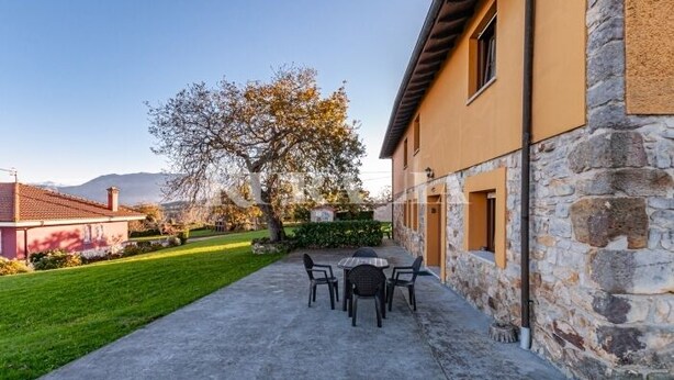 A building with a stone facade and a paved patio area with outdoor seating. - Apto Tapia 2 - rural apartment in Luces (Colunga), Northern Spain | 6 guests (San Telmo)