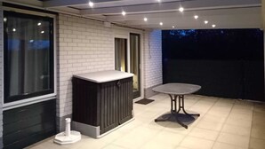 A covered patio area with a table and a heater, a window, and a door.
