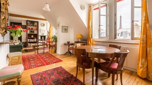 Une pièce chaleureuse avec une table à manger, des chaises, une bibliothèque et une vue sur la Tour Eiffel.