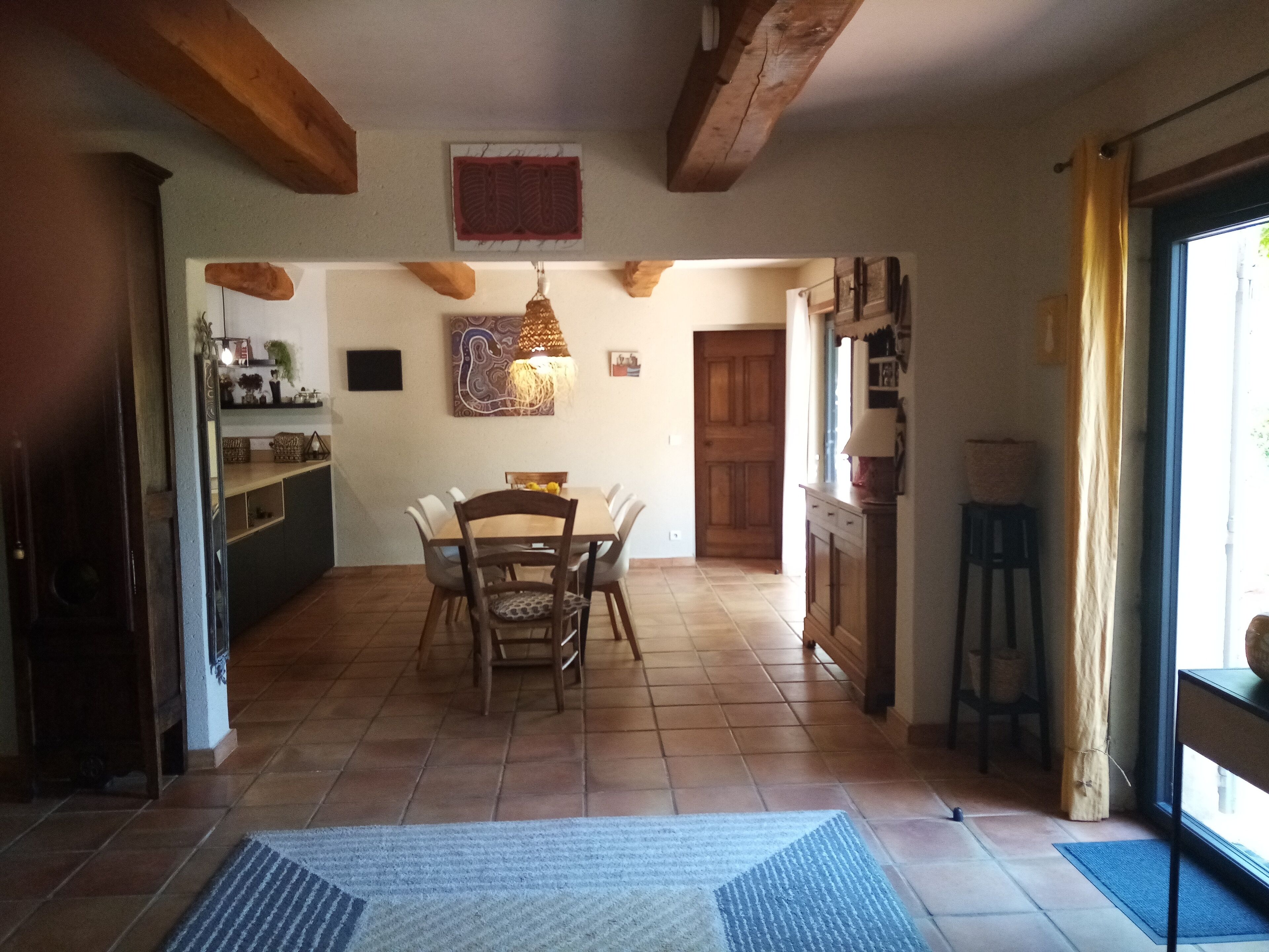 A spacious kitchen with a dining area, wooden beams, and a large window.