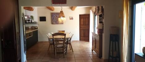 A spacious kitchen with a dining area, wooden beams, and a large window.
