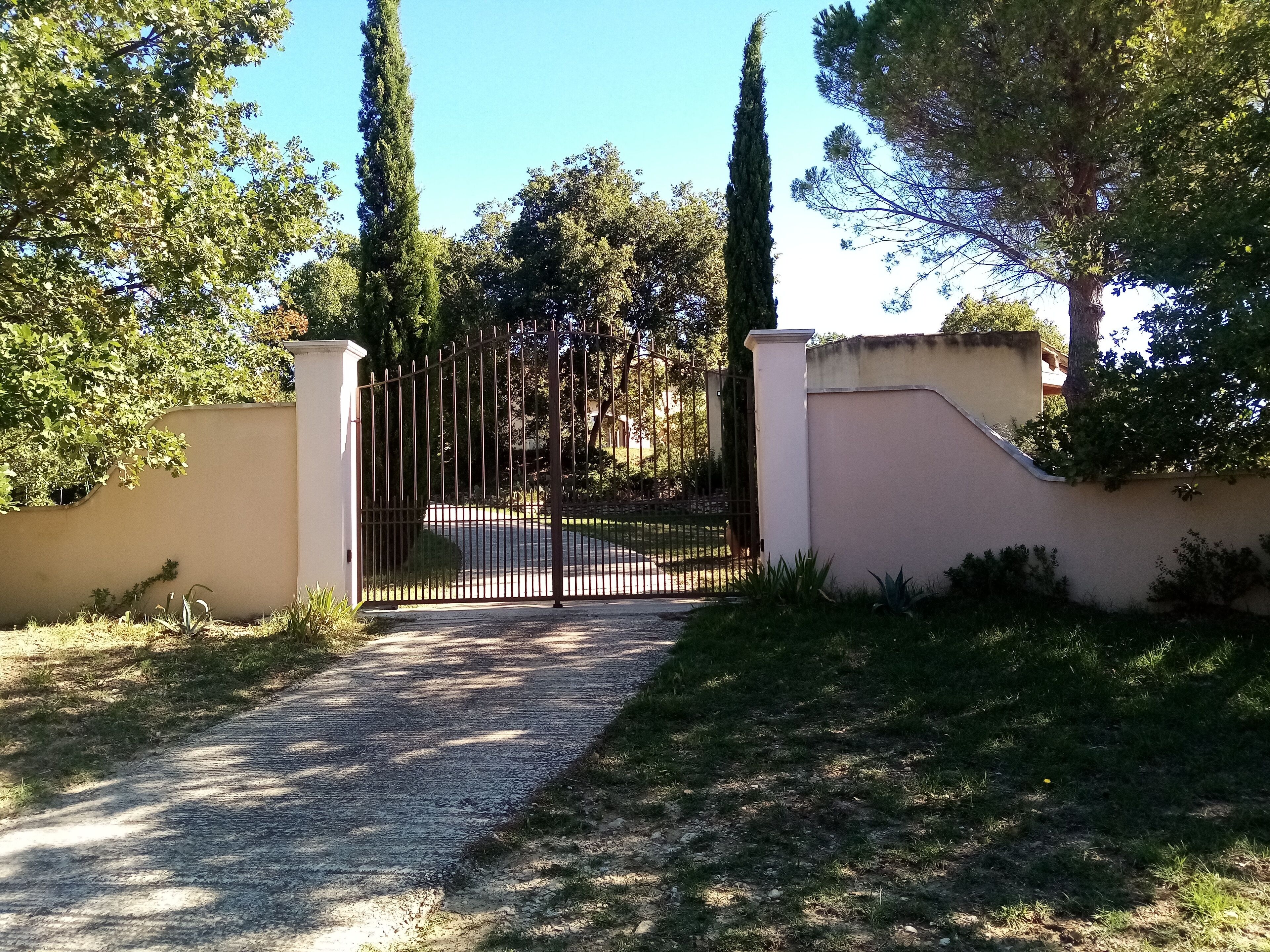 A gated entrance with a gravel path leading to a driveway.