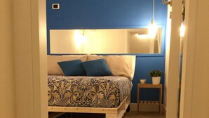 A bedroom with a bed, a bedside table with a plant, and a mirror on the wall. - Luxurious relaxation in town! (Napoli)