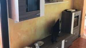 Una sala de estar moderna con un televisor de pantalla plana montado en la pared, una mesa de centro con adornos y un mueble empotrado con estantes.