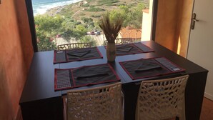 Una mesa con cuatro individuales y dos sillas, con vistas a un paisaje costero y montañas al fondo.