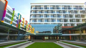 A modern building with a central courtyard, multiple floors, and a mix of colorful and white facades. - Stay Awhile at Aeropod Sovo Studio (Kota Kinabalu)