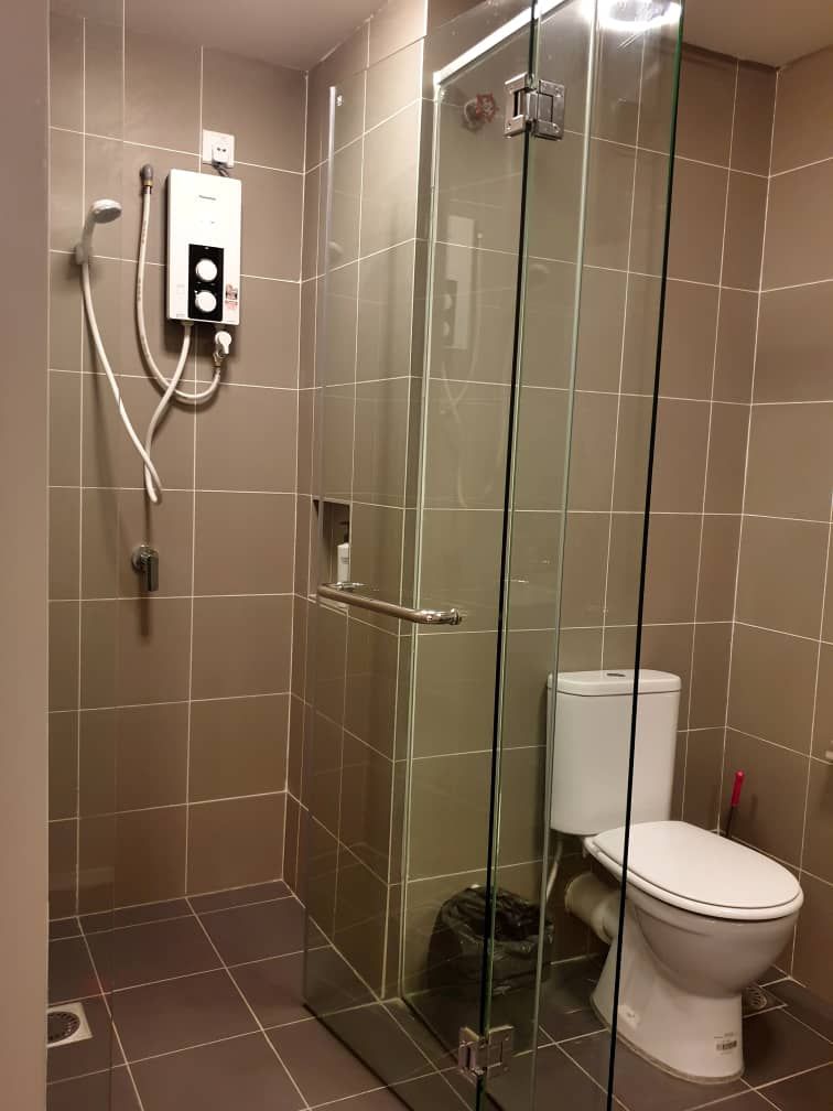 A glass-enclosed shower stall with a white toilet and a control panel.