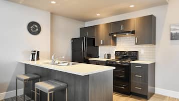 A modern kitchen with a central island, stainless steel appliances, and dark wood cabinets.