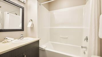 Un baño con bañera, lavabo y espejo.